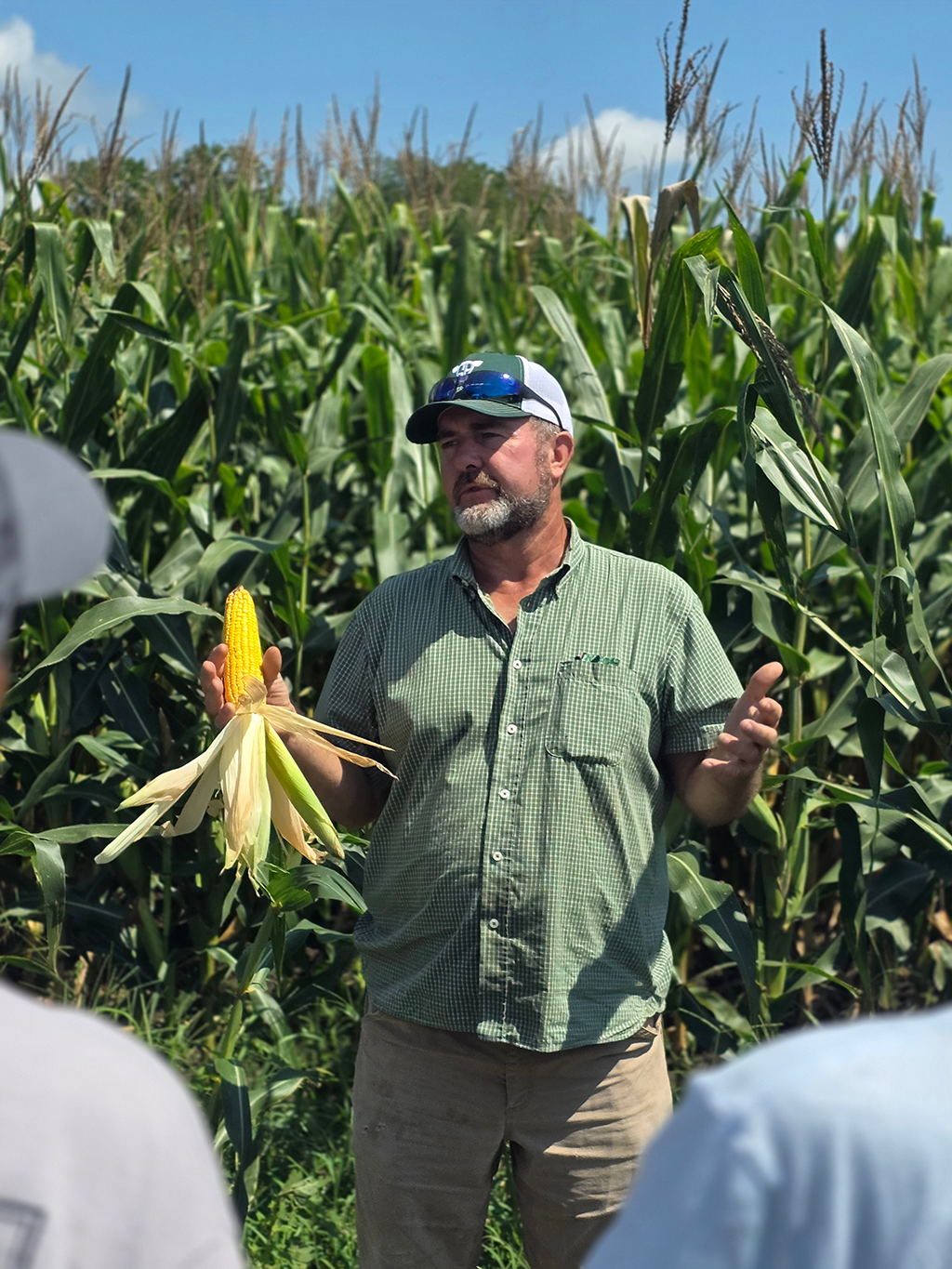 Jack Geiger holding an ear of corn while addressing the crowd